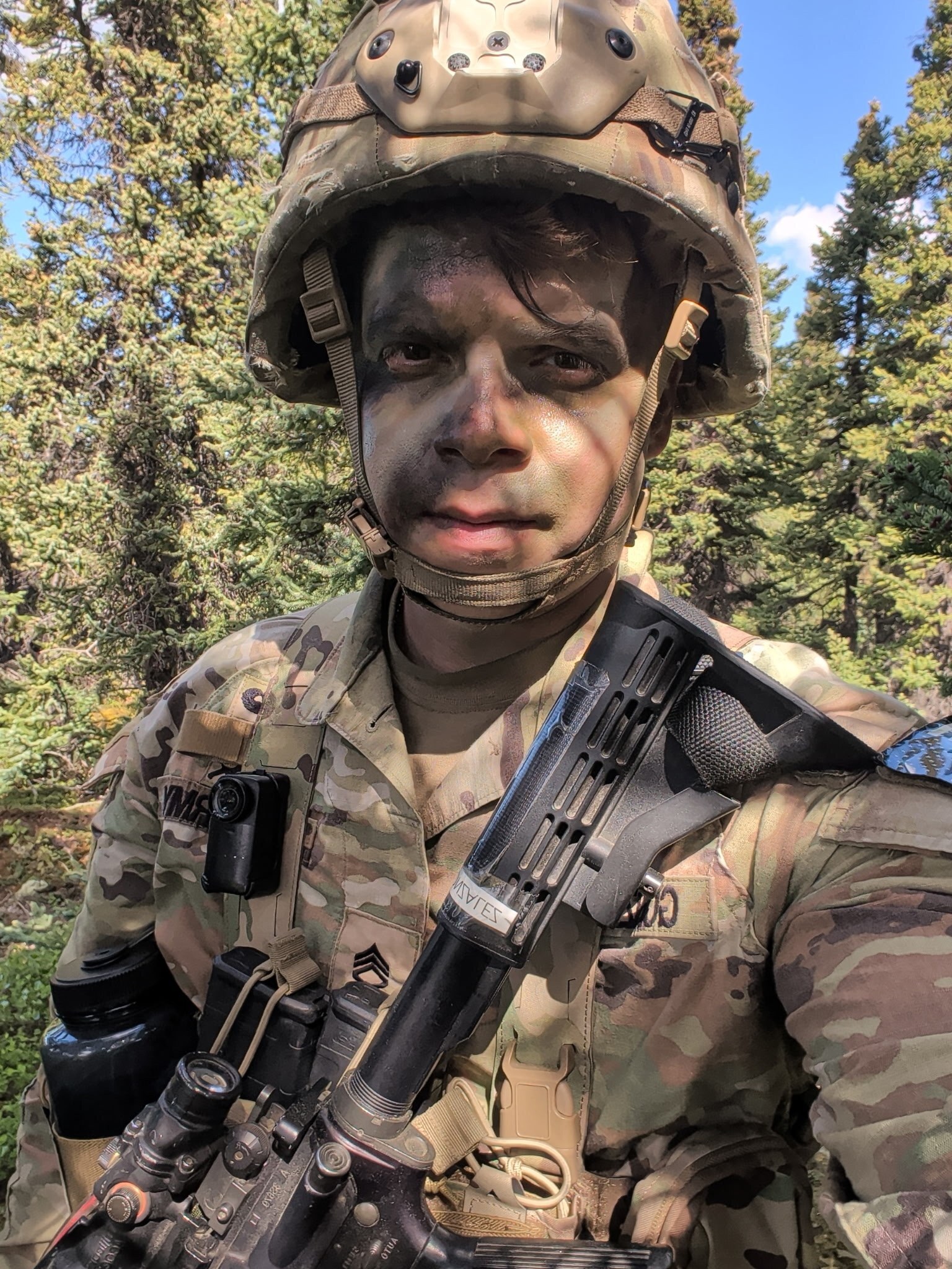 Staff Sgt. Joel Gonzalez in camouflage face paint and helmet during field training